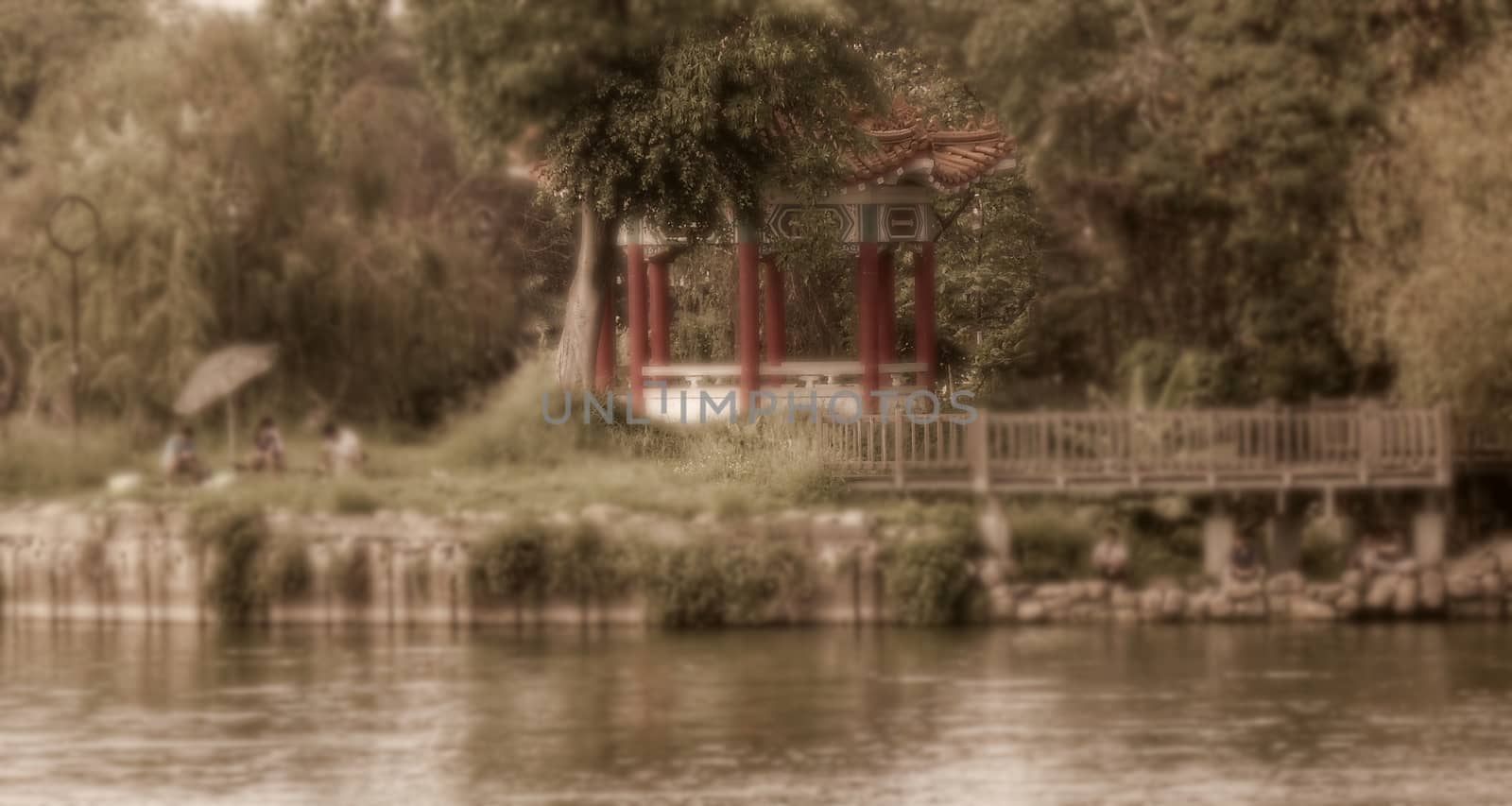 Vintage style image with selective focus of people relaxing by the lakeside in the heat of summer
