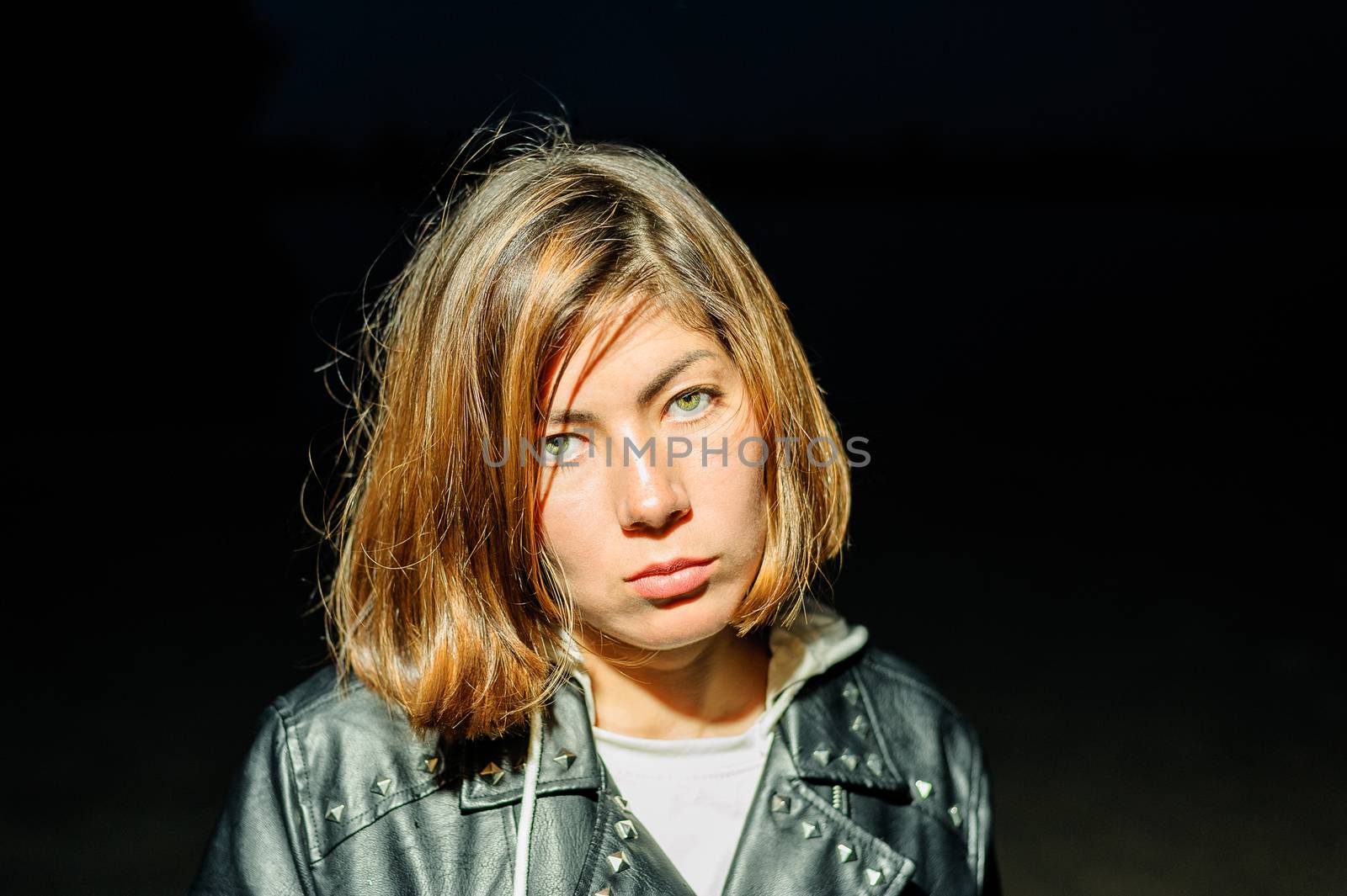 girl with a serious face in a leather jacket on a black background