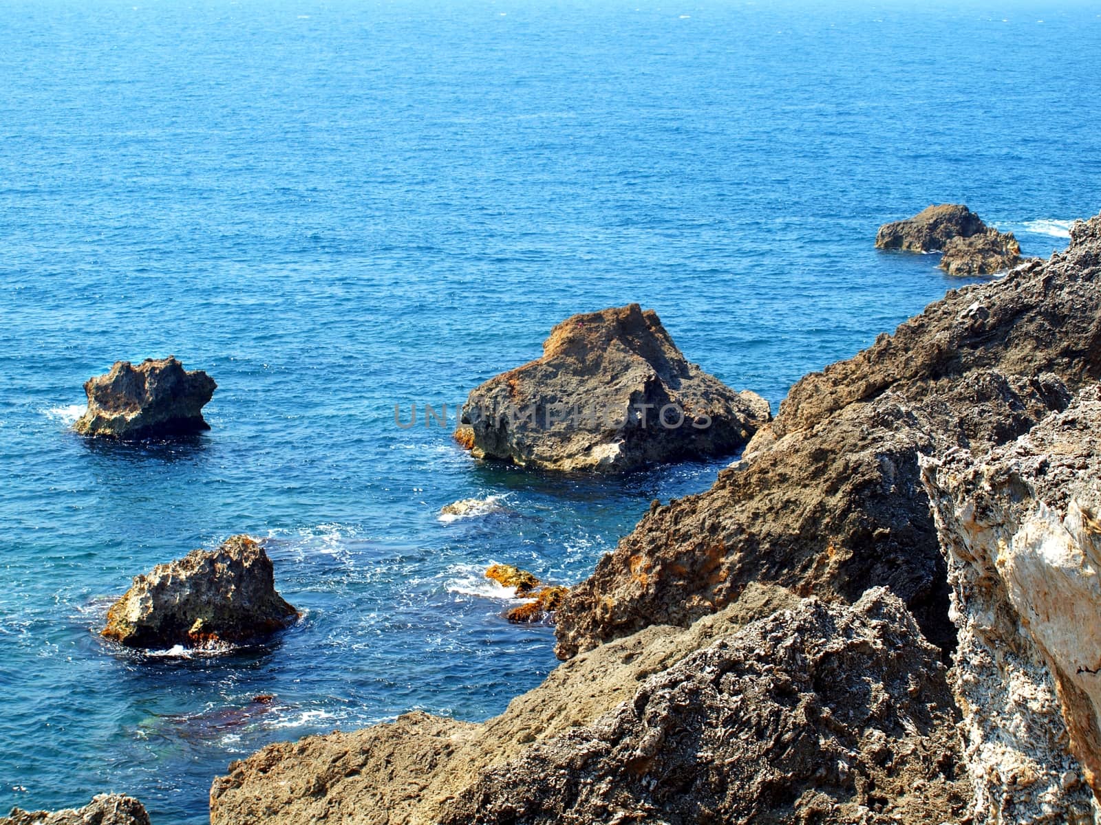 Steep cliffs of coral rock descend into a blue sea
