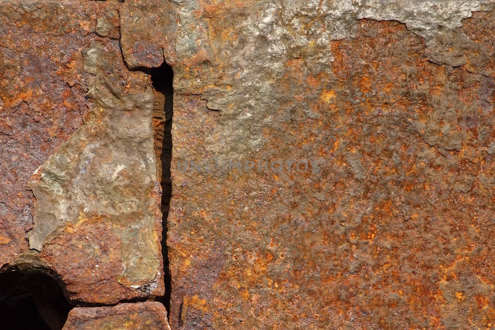 A large iron plate with a hole that is heavily corroded by rust
