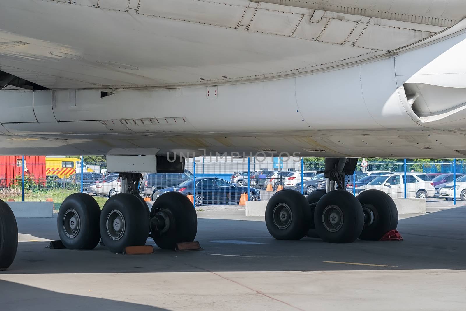 chassis, wheels and bottom of the aircraft in the Parking lot of the treadmill on the background of the fence at the airport, behind which there is a car Parking