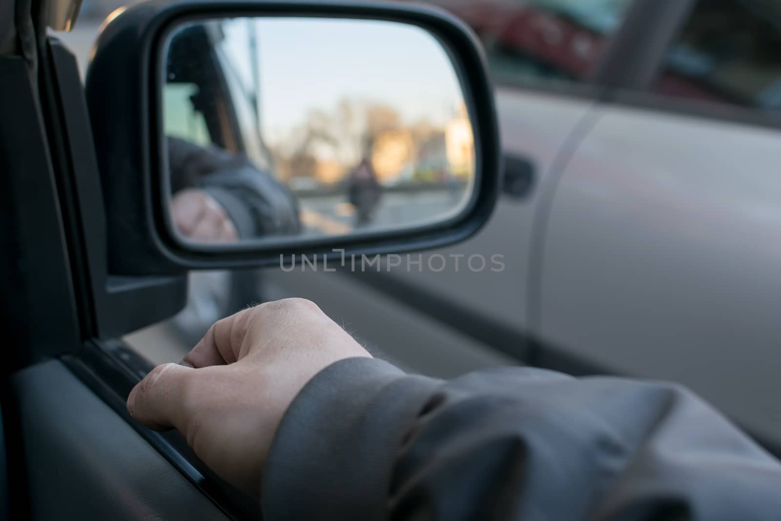 a man hand on the car door on the background of a female silhouette in the mirror of the rear view mirror