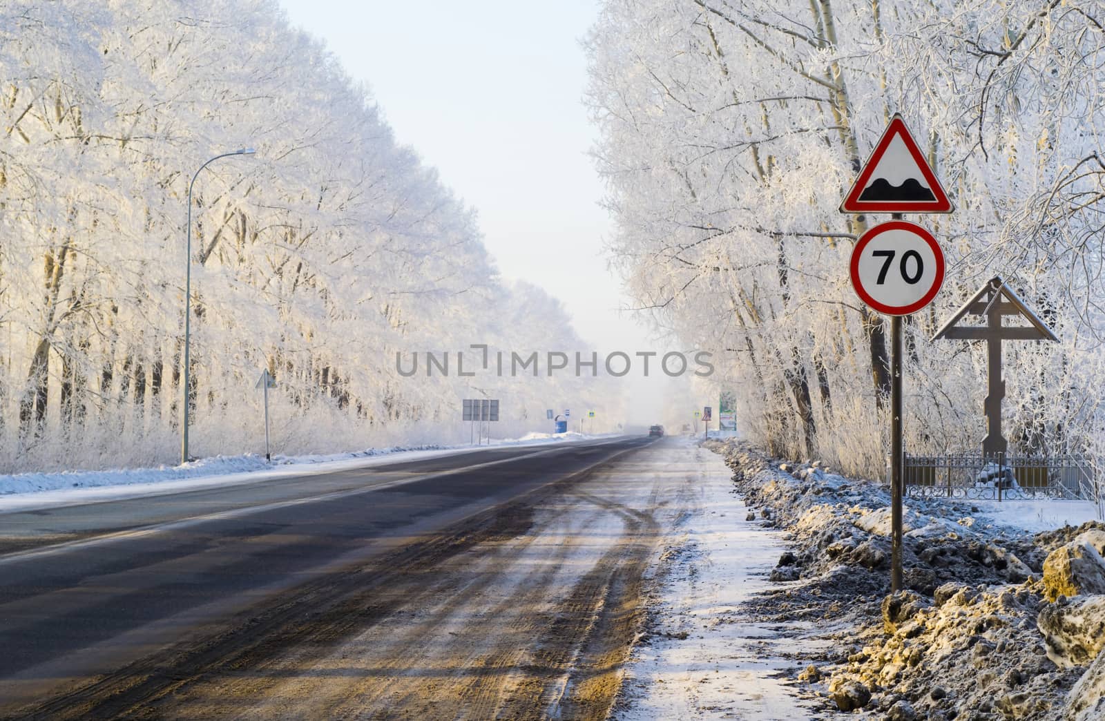 Road sign and the road surrounded by snow-covered trees