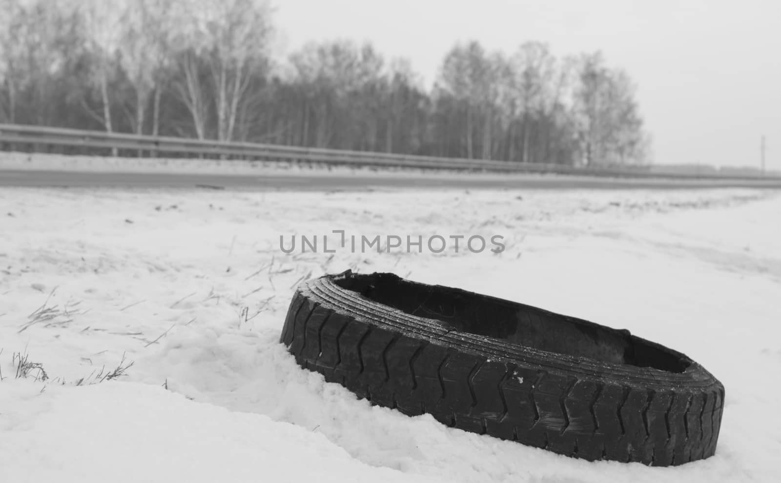 damaged tyre on the roadside of the winter road