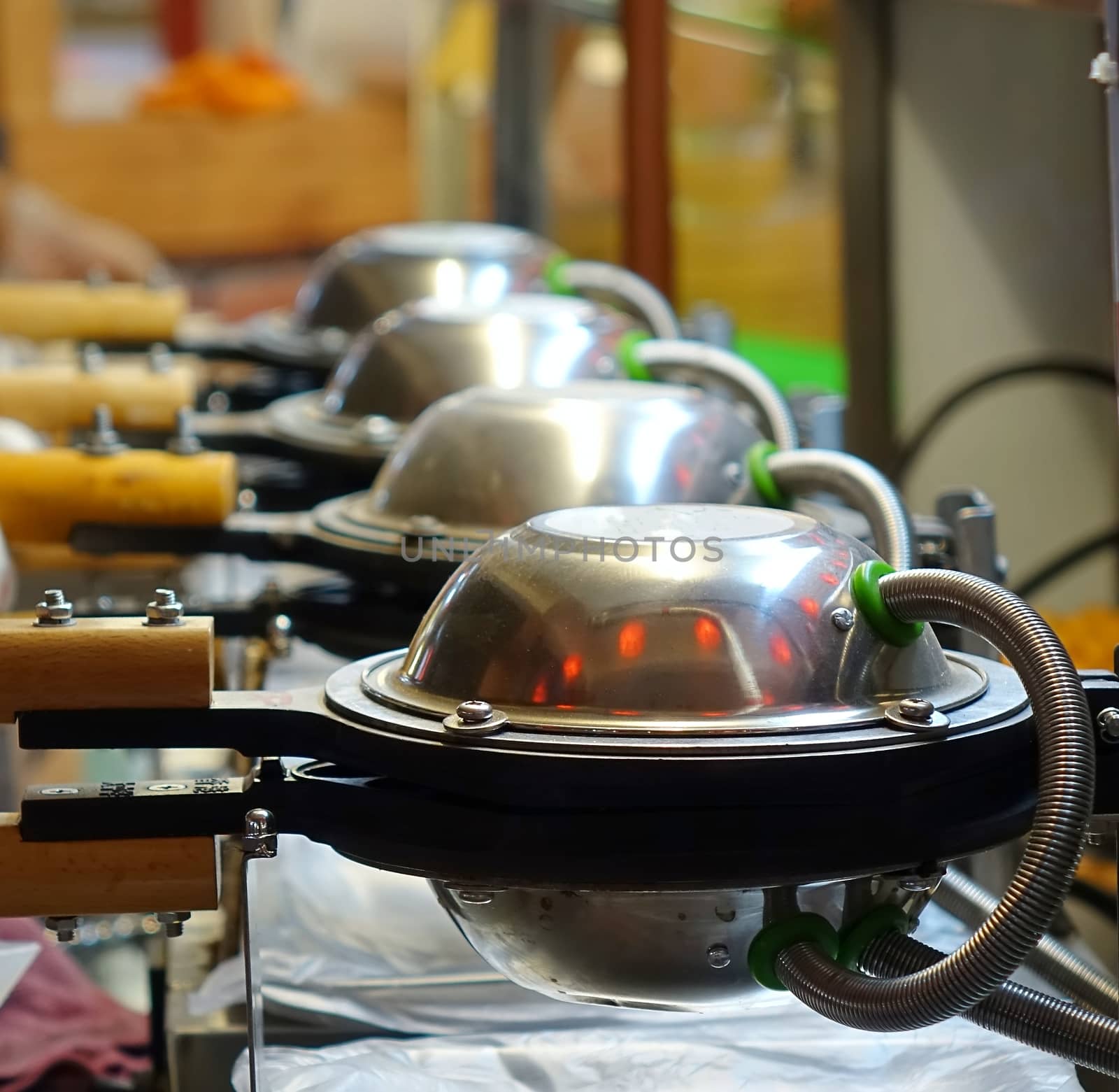 An outdoor food vendor uses a row of waffle irons
