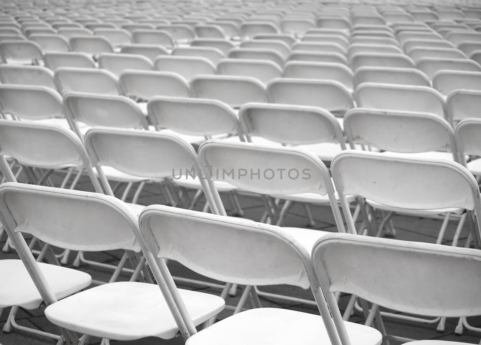 Rows of plastic chairs are set up for an outdoor  performance

