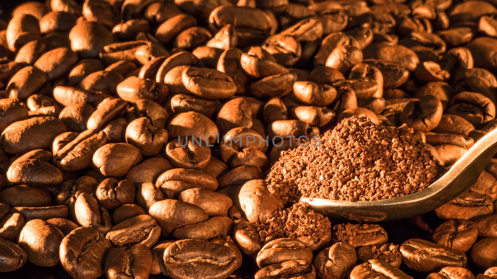 Coffee beans close-up with a spoon of ground coffee.