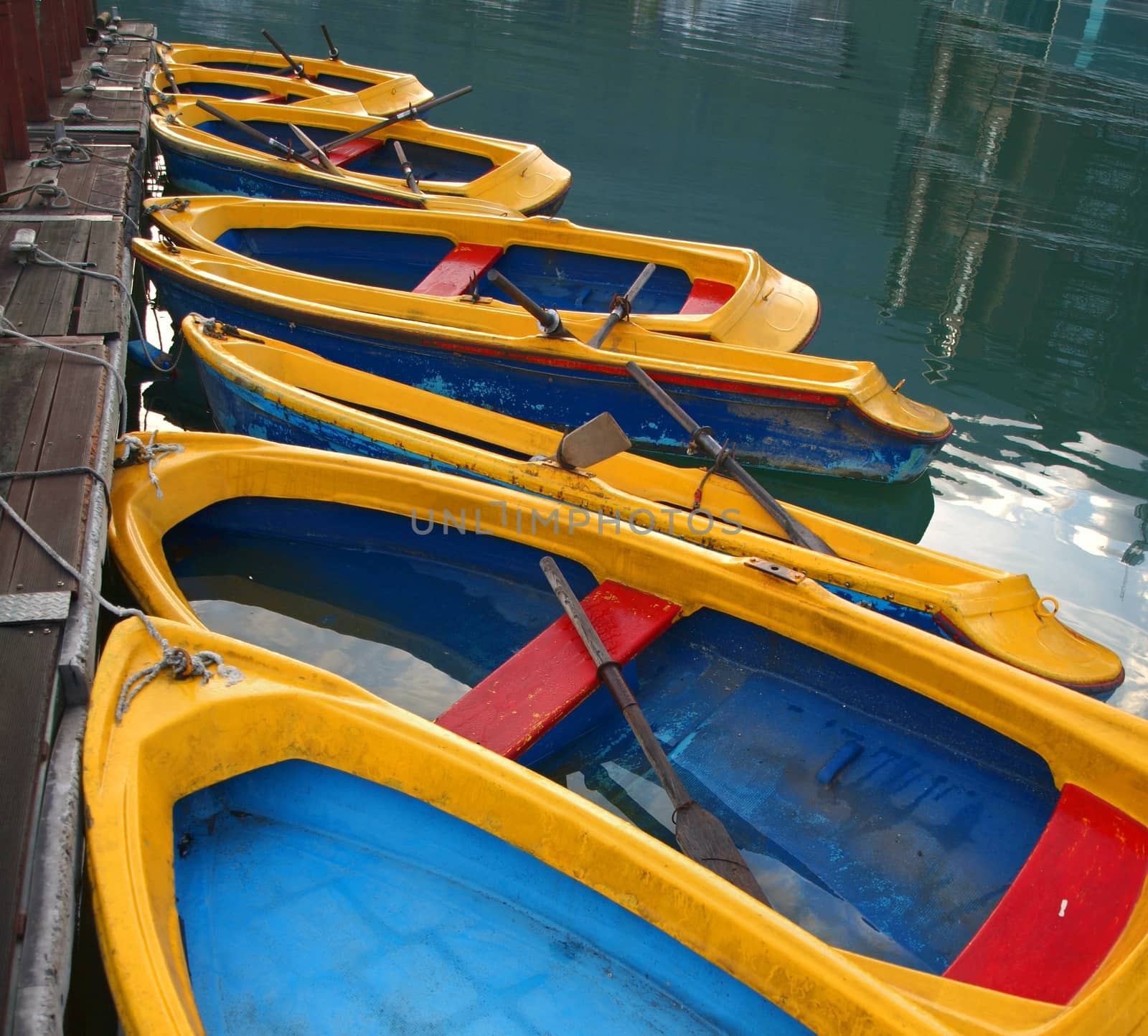 Blue and yellow rowboats are tied to a wooden pier