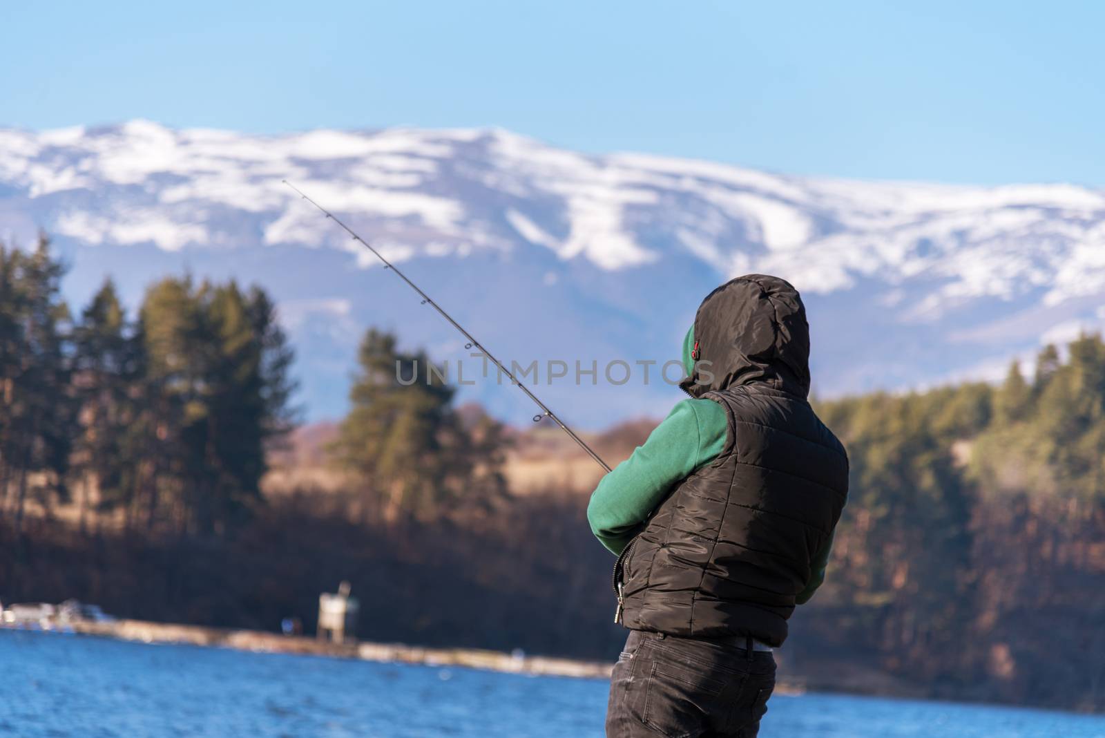 A male fisherman on the lake is standing in the water and fishing for a fishing rod. Fishing hobby vacation concept. Copy space.