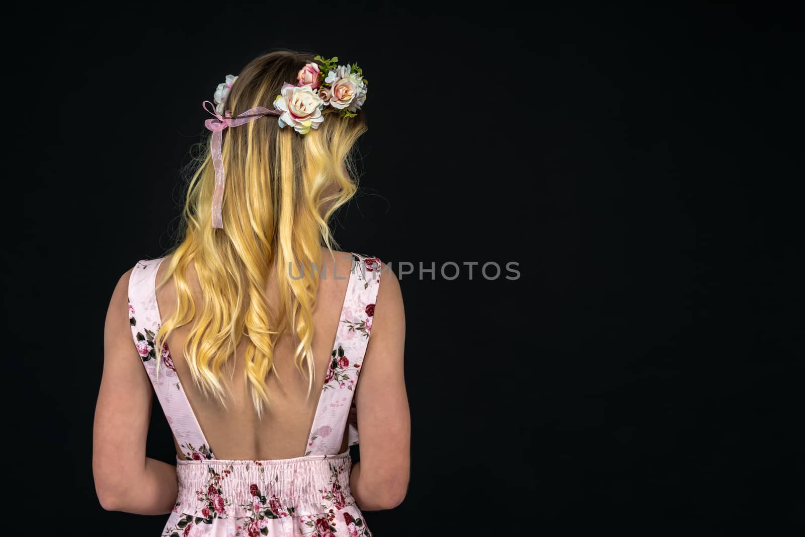 back of a young woman in a dress with golden hair. portrait on a black background whith copy space by Edophoto