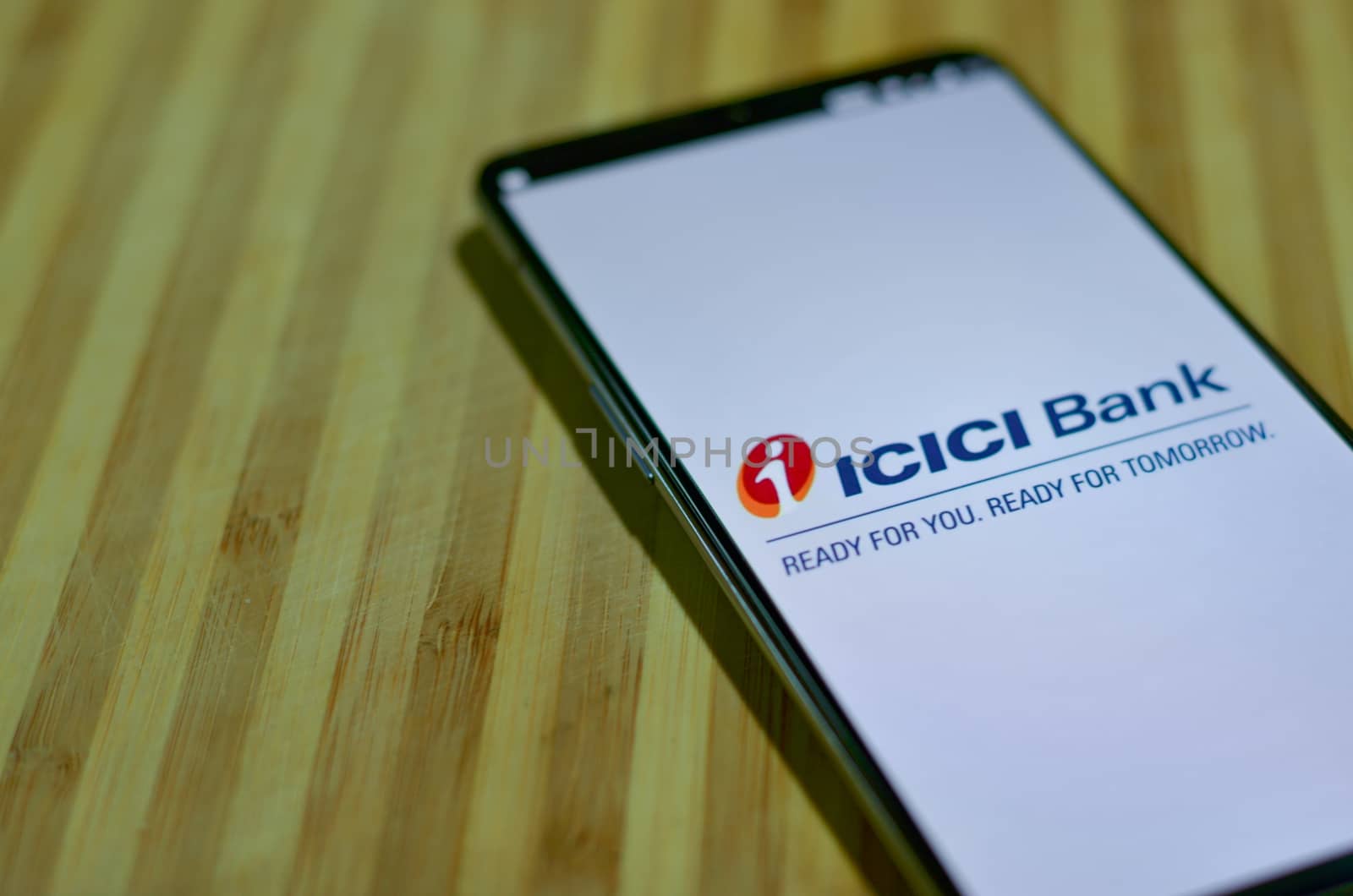 New Delhi, India, 2020. Flat lay ICICI bank app on mobile phone screen against a wooden board background. People are encouraged to not visit the bank & do digital banking transactions during lock down