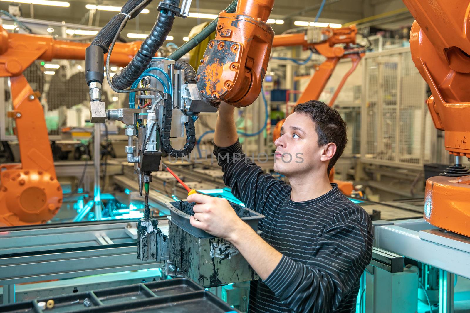 engineer performs maintenance of industrial robot in a factory.