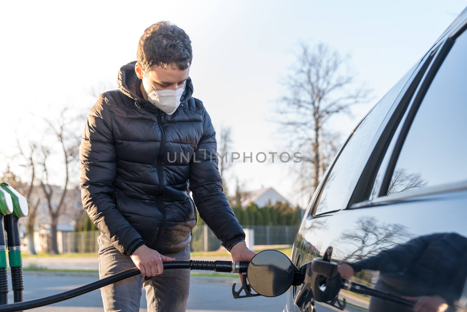 fueling the car at the time of the epidemic coronavirus with a respirator over his mouth and nose by Edophoto