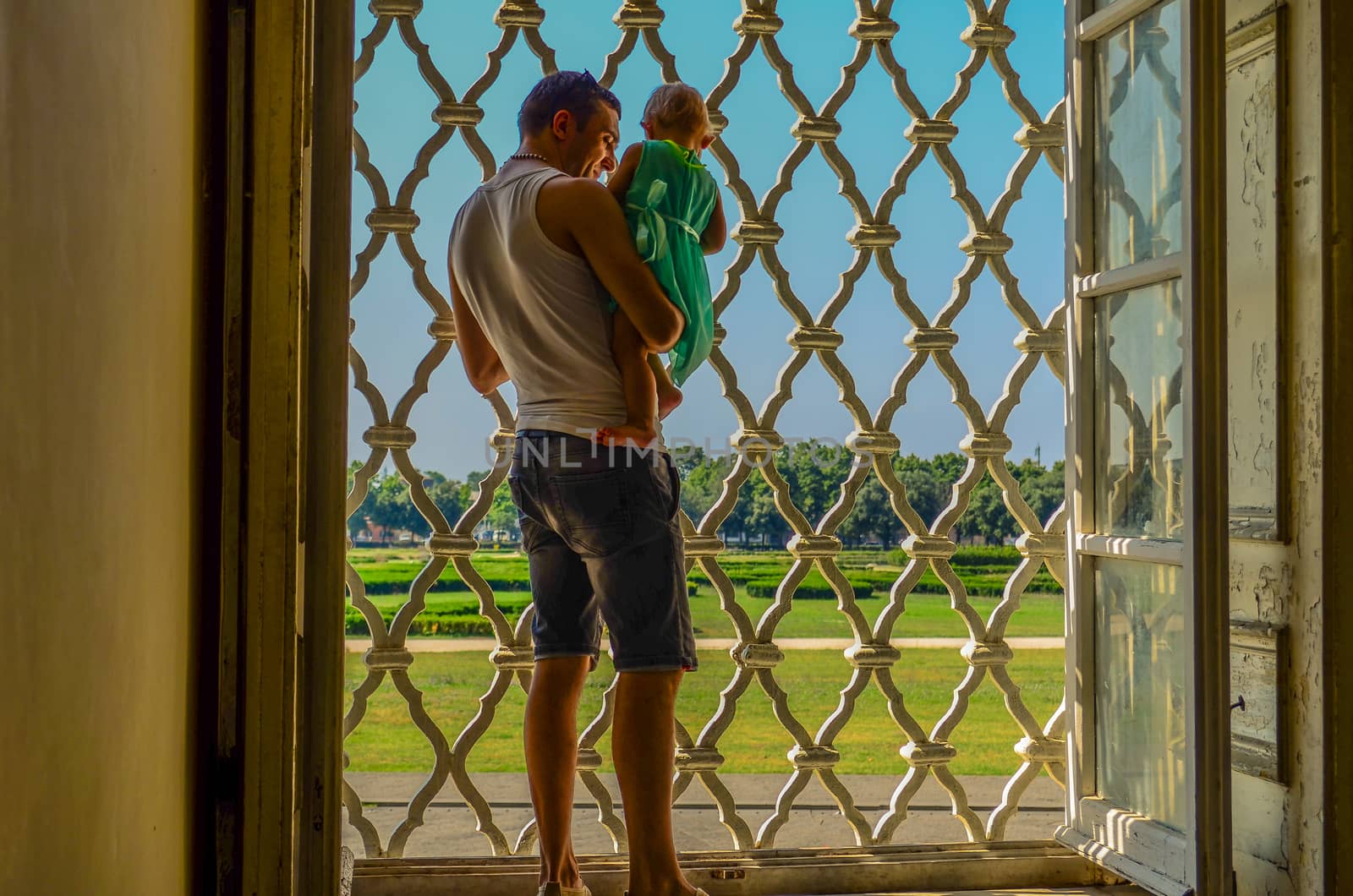 a young father with a little girl in his arms looking through the window