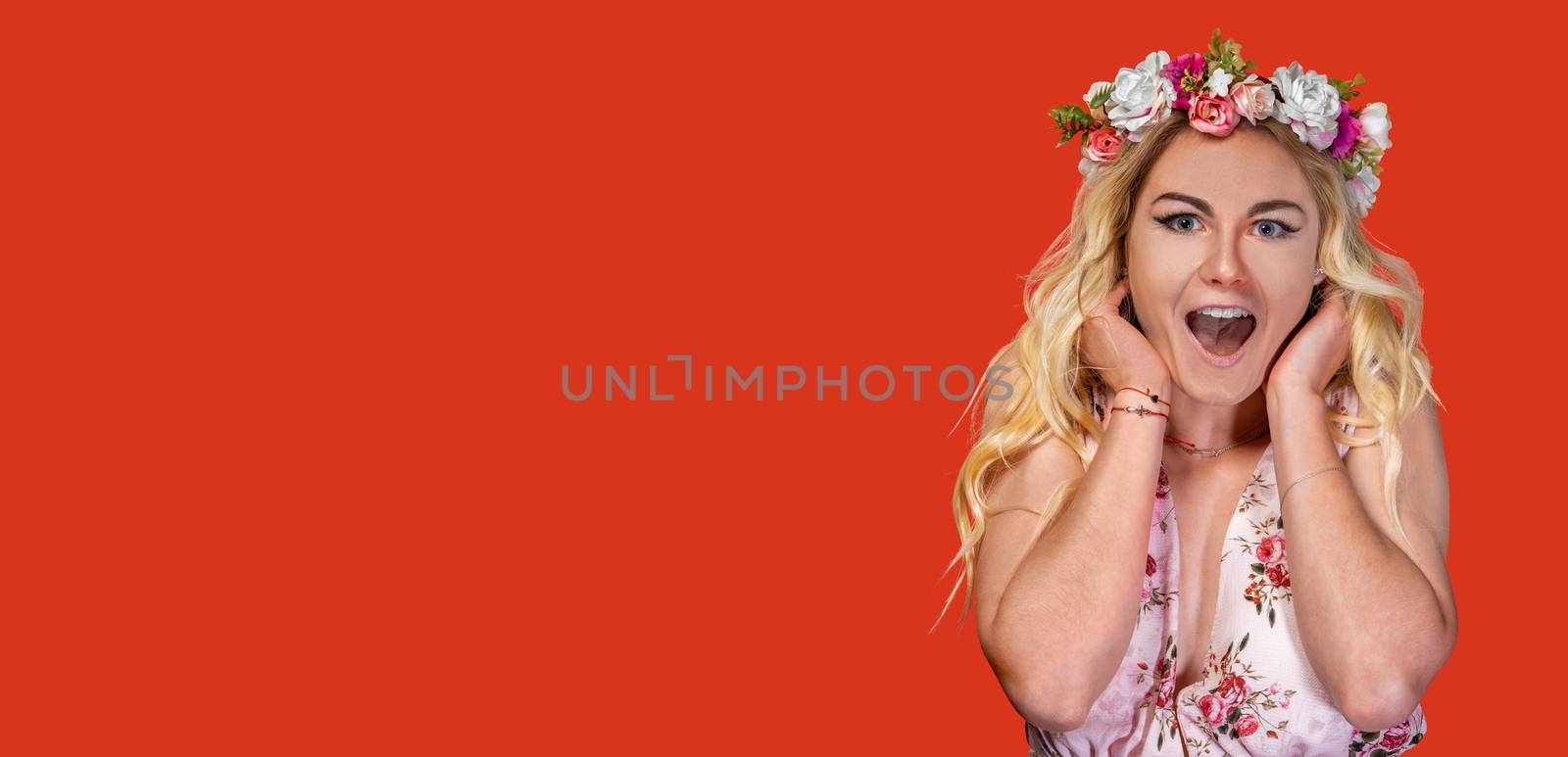 happy woman in a dress with a flower wreath on her head. Portrait on a red background. Banner with copy space.