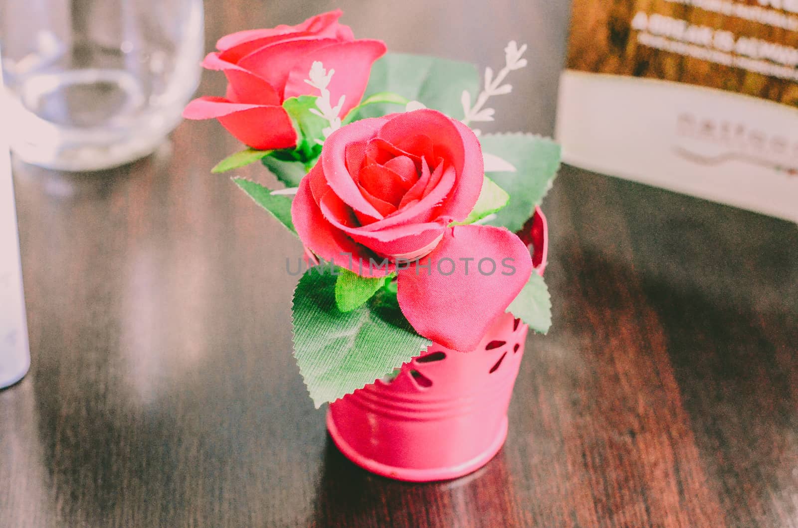 a bouquet of decorative pink roses stands in an iron pail on the table