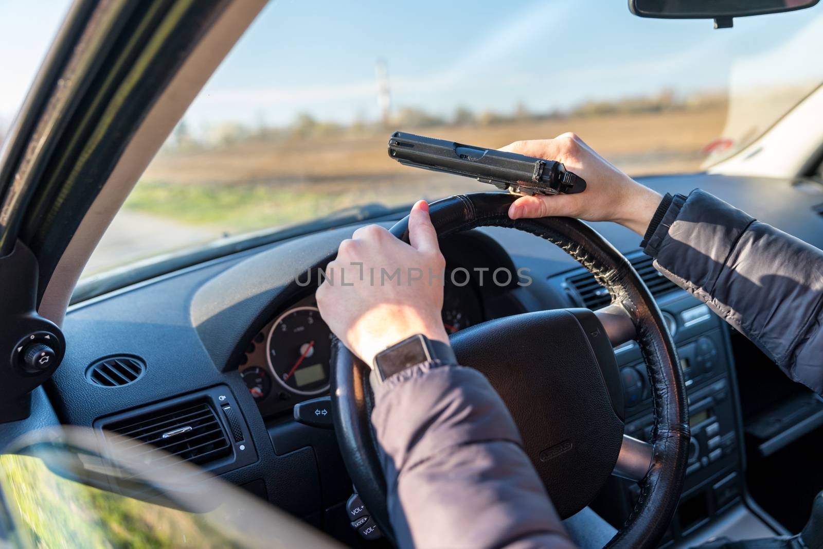 young man with gun in hand in passenger car on driver's seat.