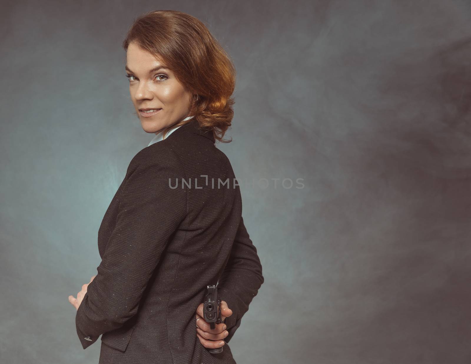 Portrait of woman with gun on grey background, Copy space by Edophoto