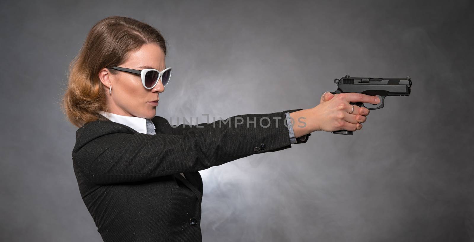 woman holding gun with both hands and aiming at target by Edophoto