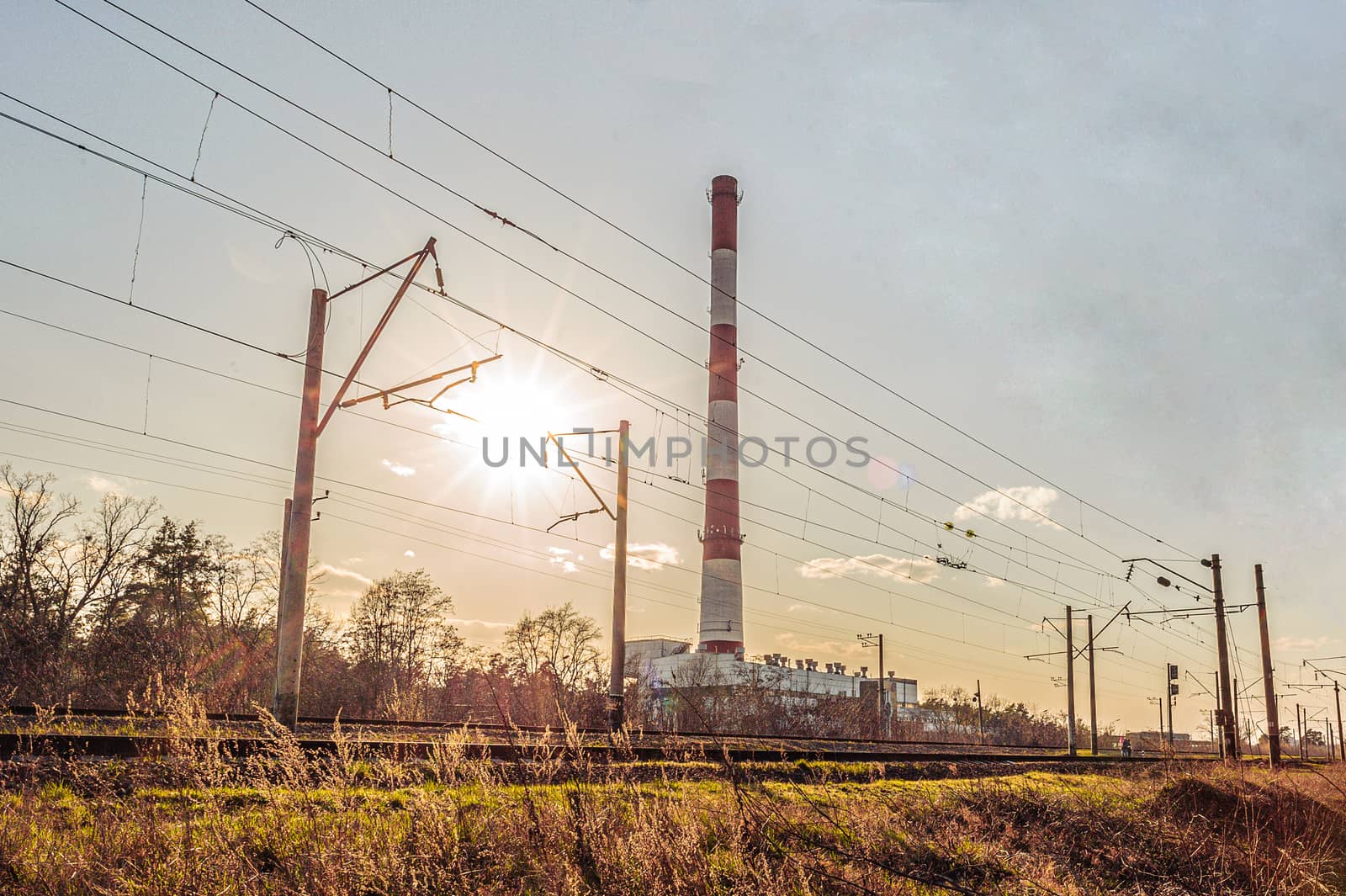 High pipe of thermal power station near the railway at sunset by chernobrovin