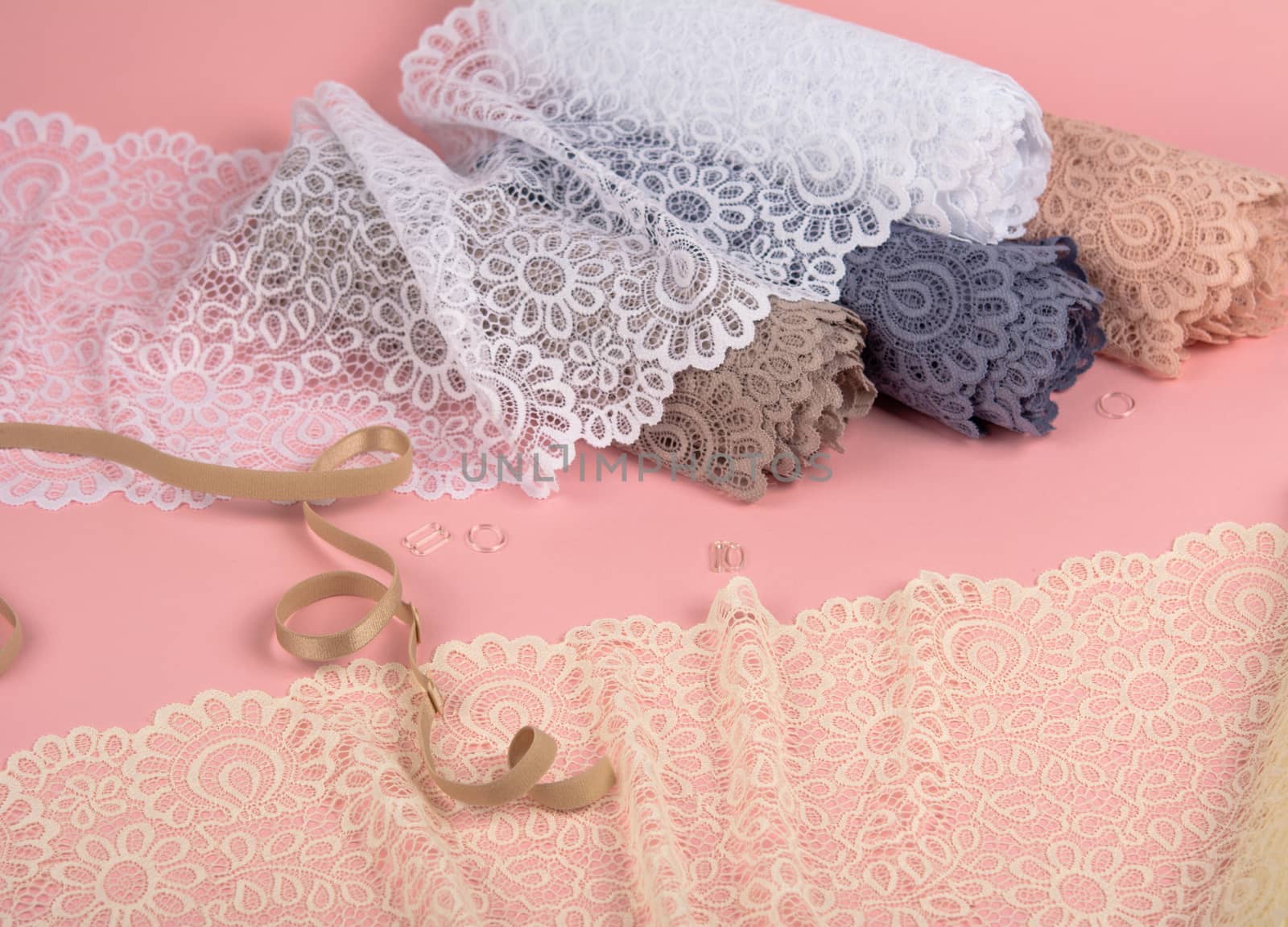Roll of Delicate laces for panties and bras on pink background with plastic fittings. Elastic material. Using for Atelier and fabric store. by polyats