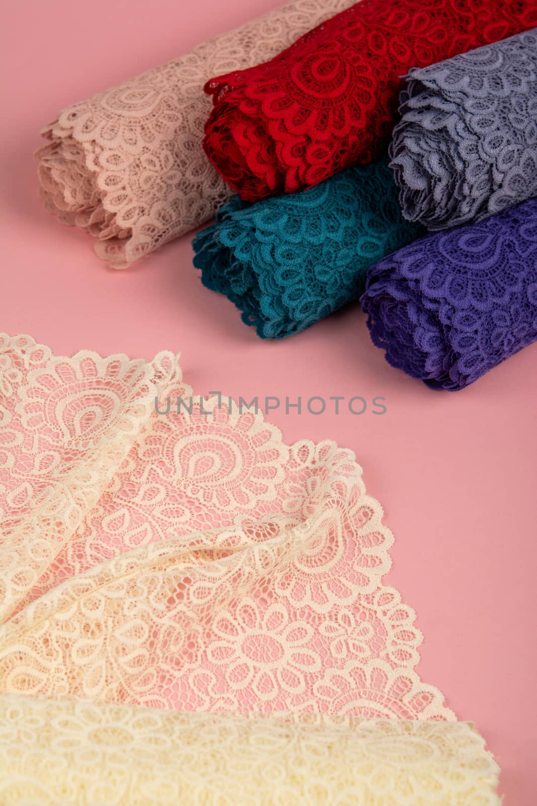 Roll of Delicate laces for panties and bras on pink background with plastic fittings. Elastic material. Using for Atelier and fabric store. by polyats