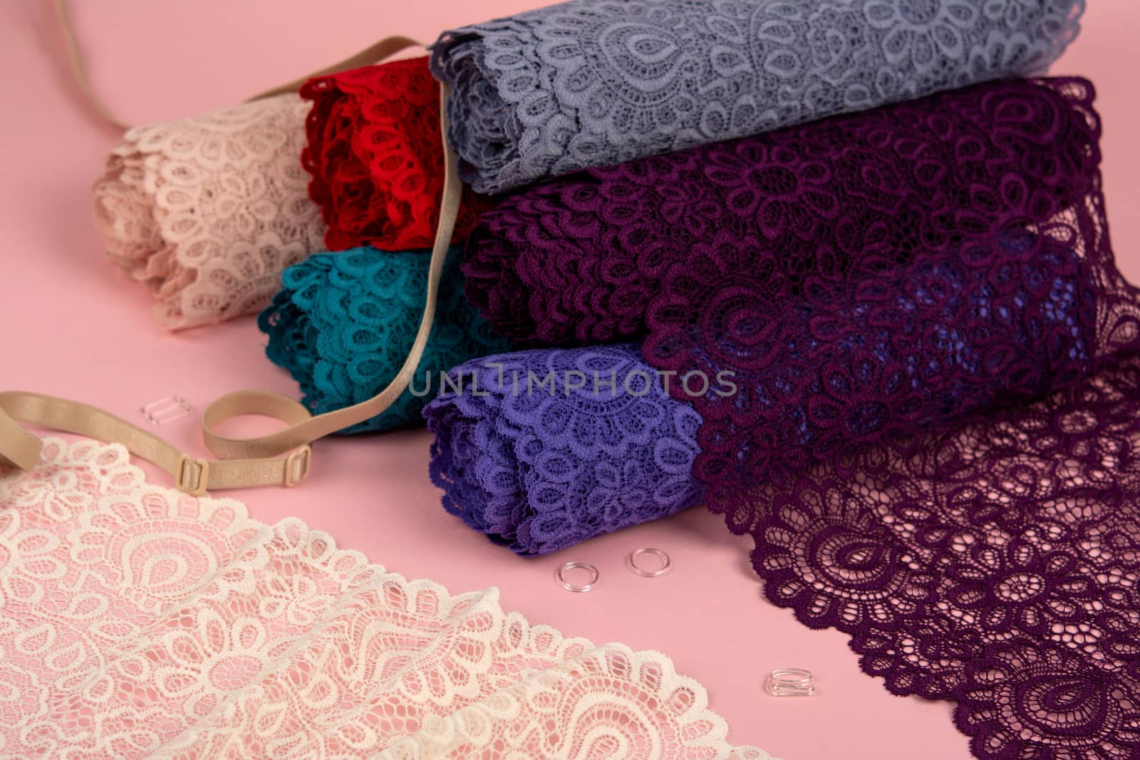 Roll of Delicate laces for panties and bras on pink background with plastic fittings. Elastic material. Using for Atelier and fabric store. by polyats