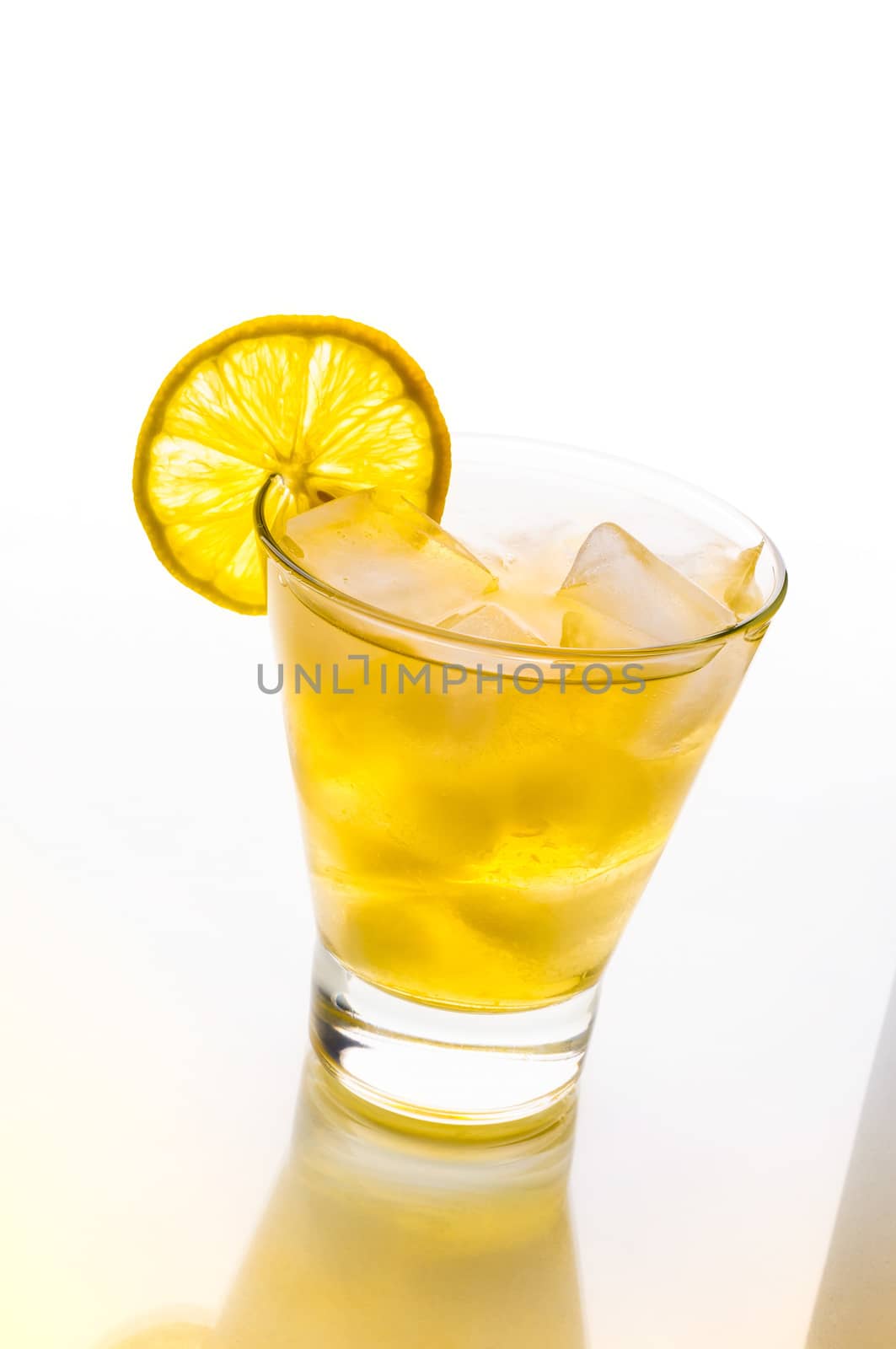 A fresh and tasty cocktail with alcohol and lemon on a glass table with yellow reflection