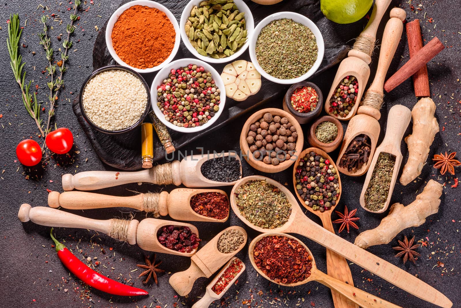 A set of spices and herbs. Indian cuisine. Pepper, salt, paprika, basil and other on a dark background. Top view. Free copy space