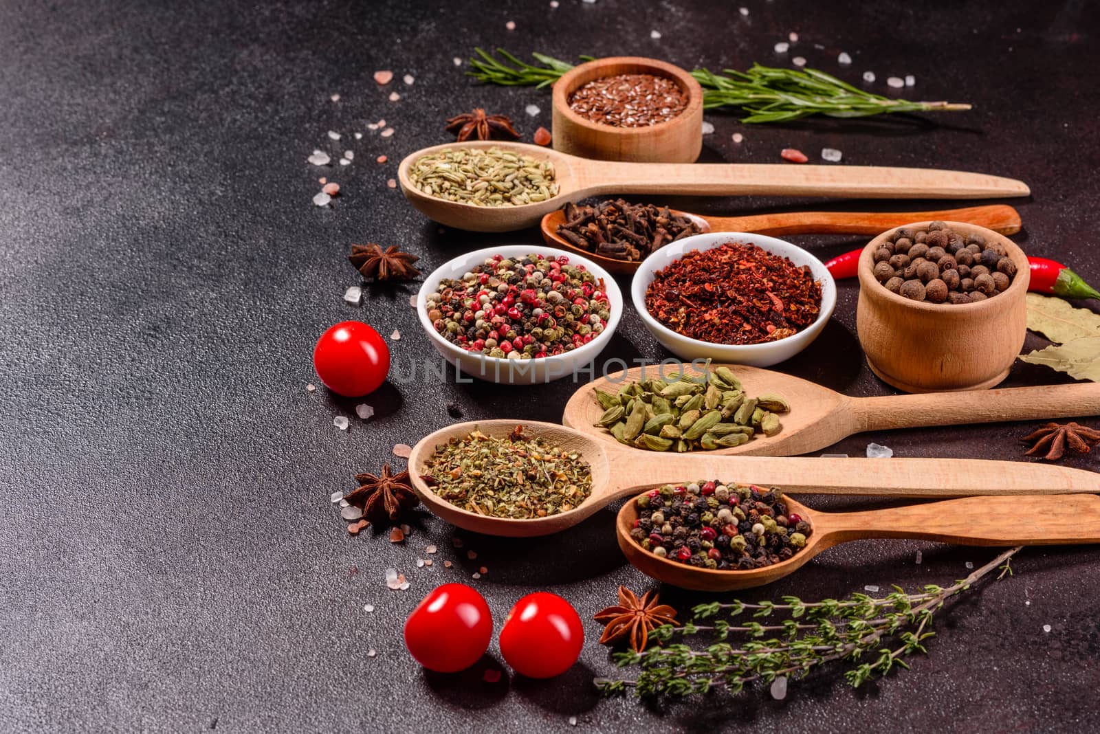 A set of spices and herbs. Indian cuisine. Pepper, salt, paprika, basil and other on a dark background. Top view. Free copy space.