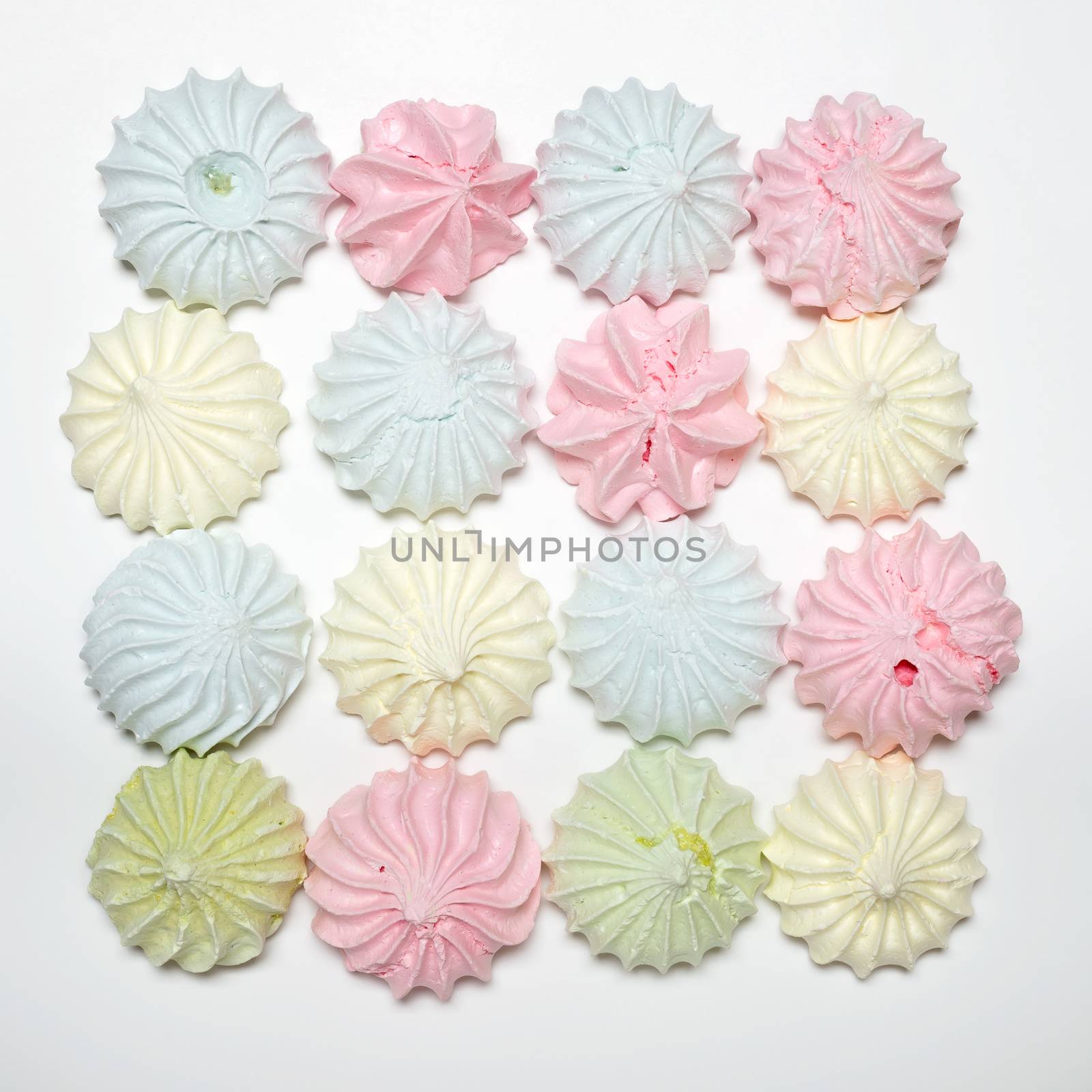 Sixteen colored french meringues aligned in a square, on white background