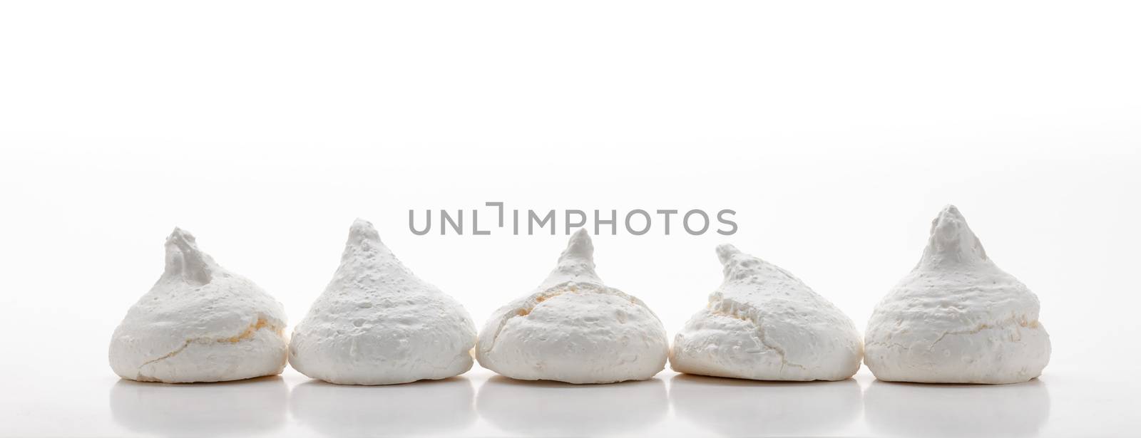 Five white french meringues aligned in a row, isolated on white background