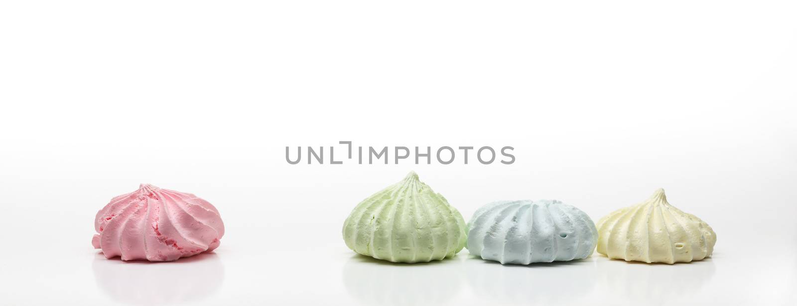 Four colored french meringues aligned in a row, on white background