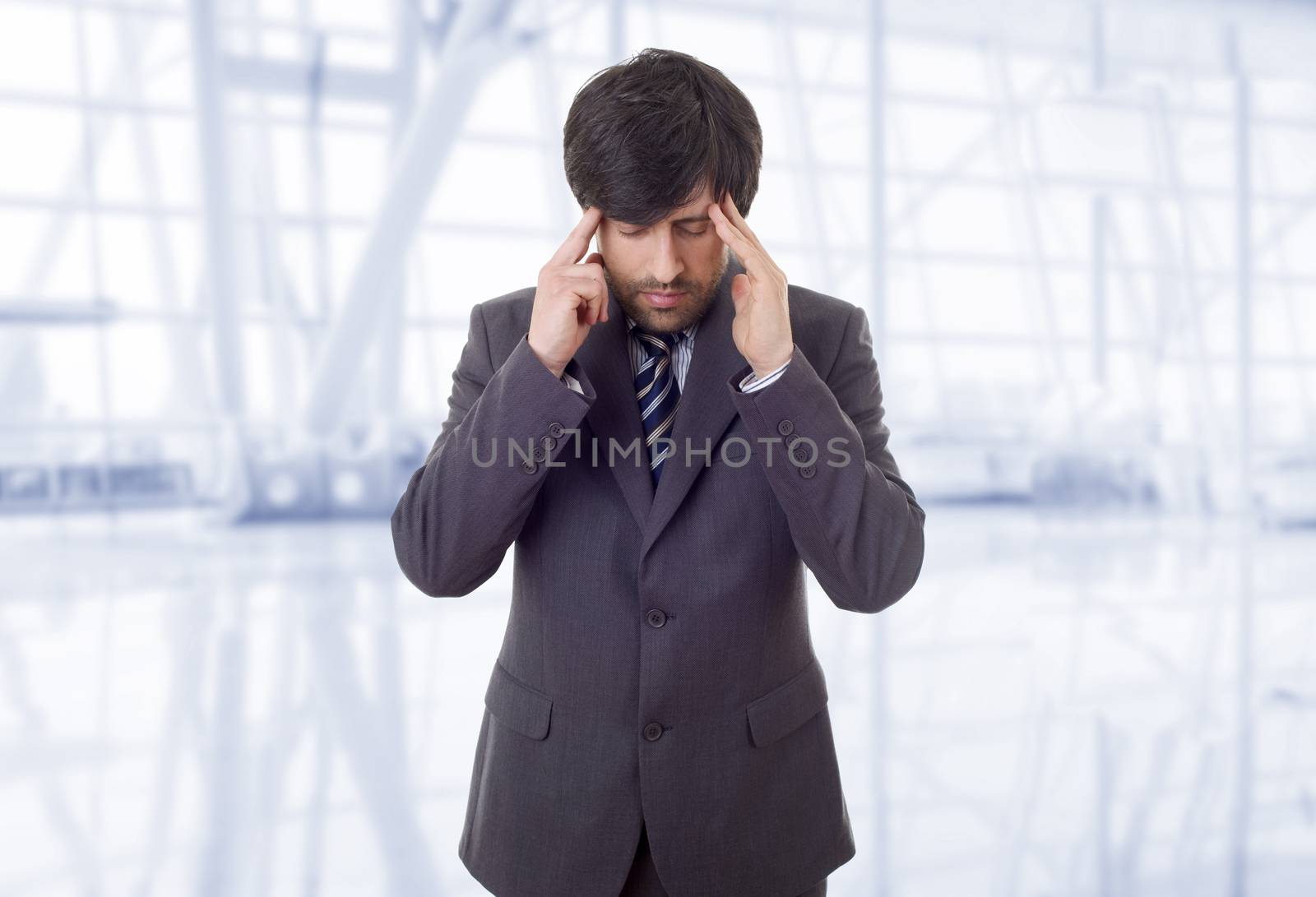 Businessman in a suit gestures with a headache, at the office