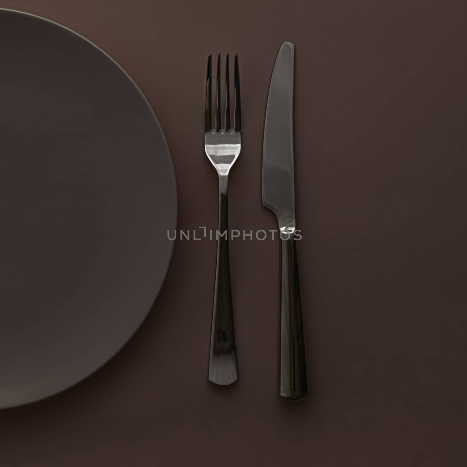 Empty plate and cutlery as mockup set on dark brown background, top tableware for chef table decor and menu branding by Anneleven