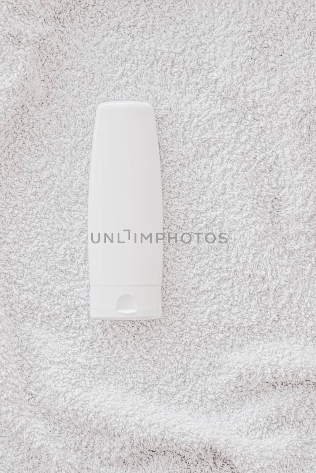 Blank label cosmetic container bottle as product mockup on white towel background, hygiene and healthcare