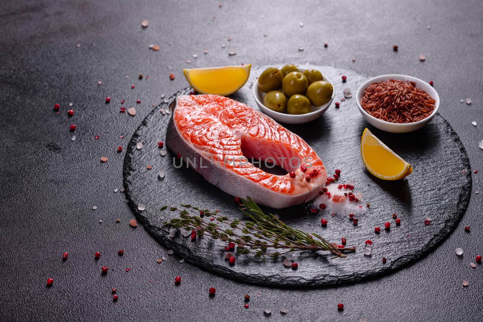 Raw trout red fish steak served with herbs and lemon and olive oil on a dark background. Cooking Salmon, sea food. Healthy eating concept