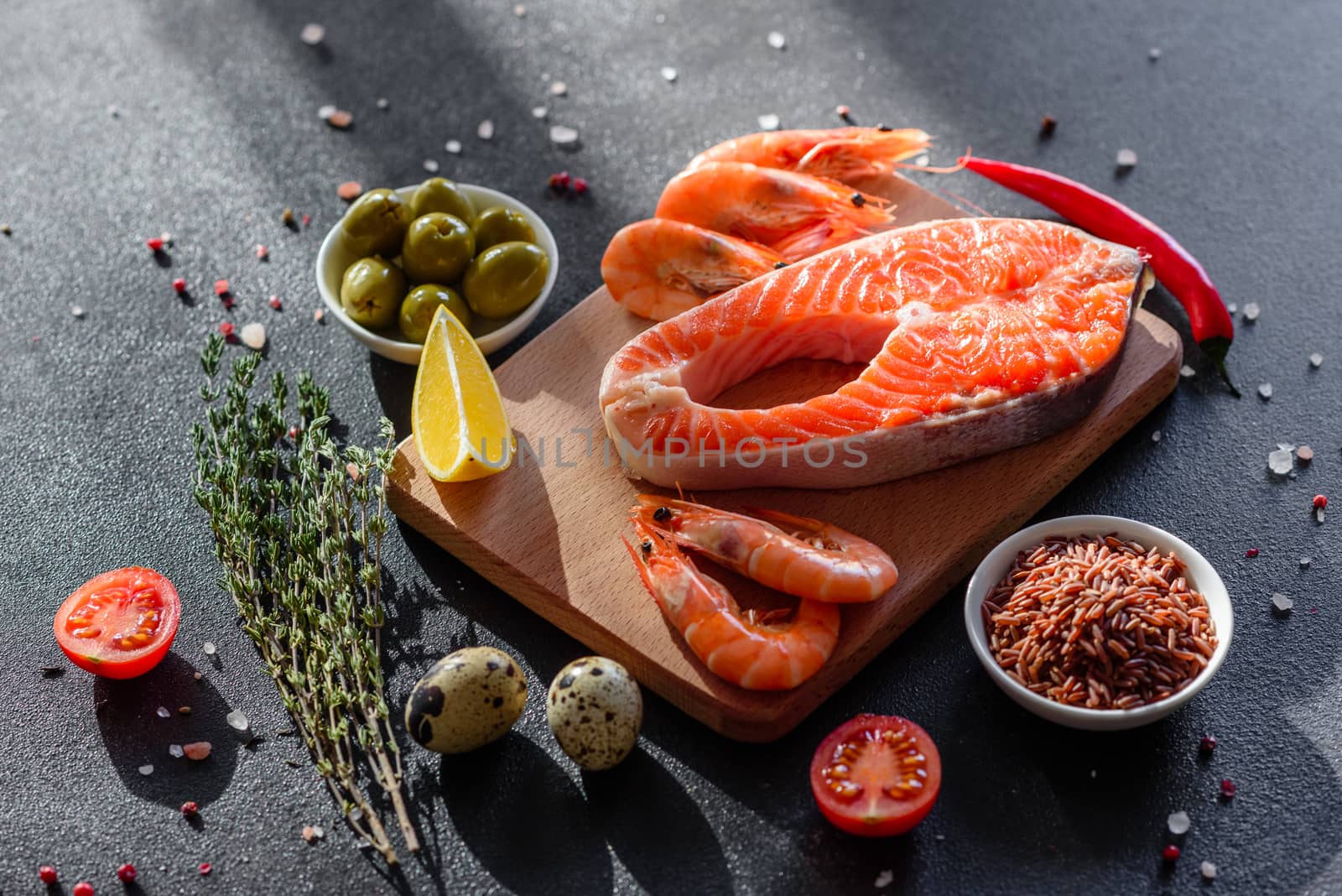 Raw trout red fish steak served with herbs and lemon and olive oil on a dark background. Cooking Salmon, sea food. Healthy eating concept