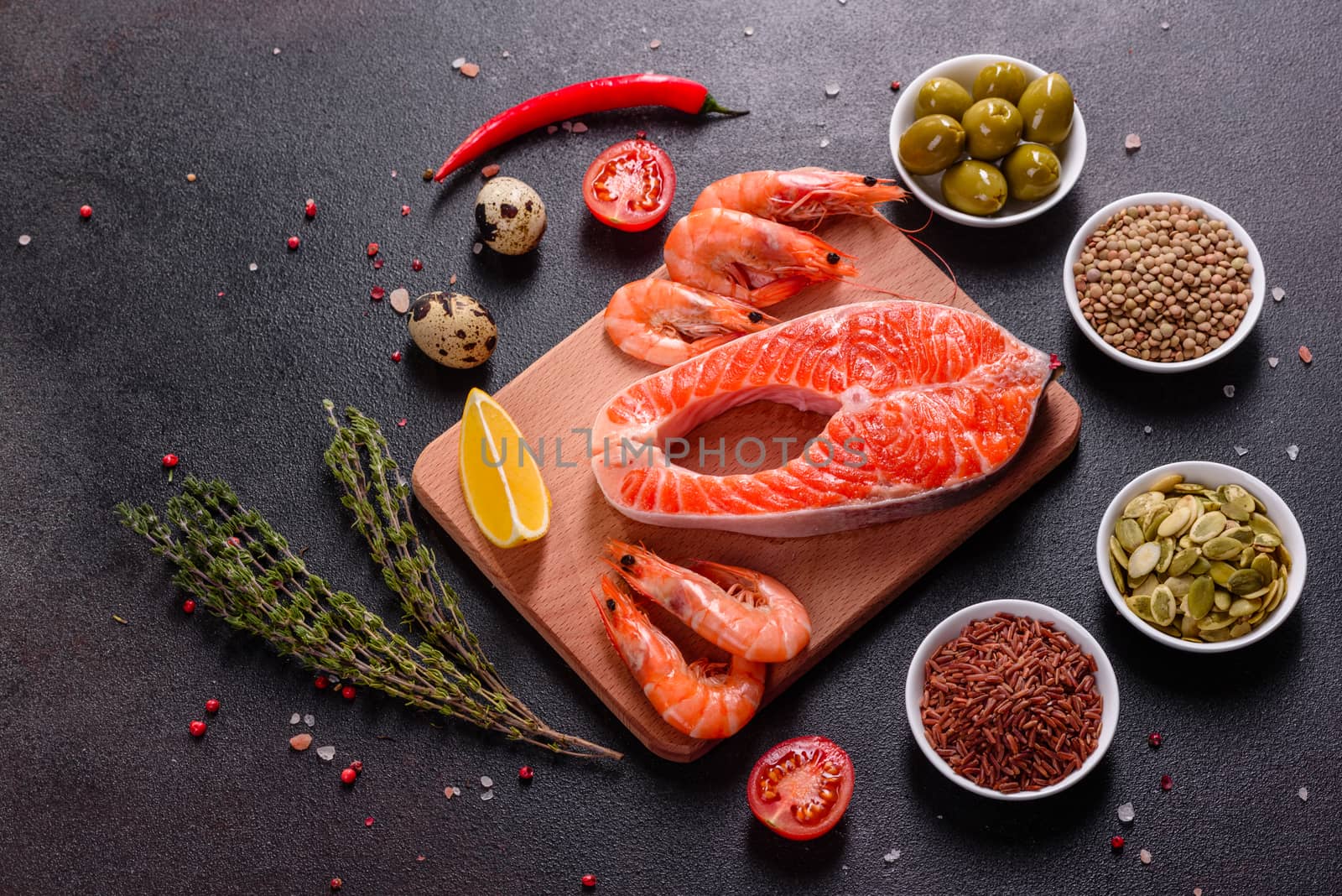 Raw trout red fish steak served with herbs and lemon and olive oil on a dark background. Cooking Salmon, sea food. Healthy eating concept