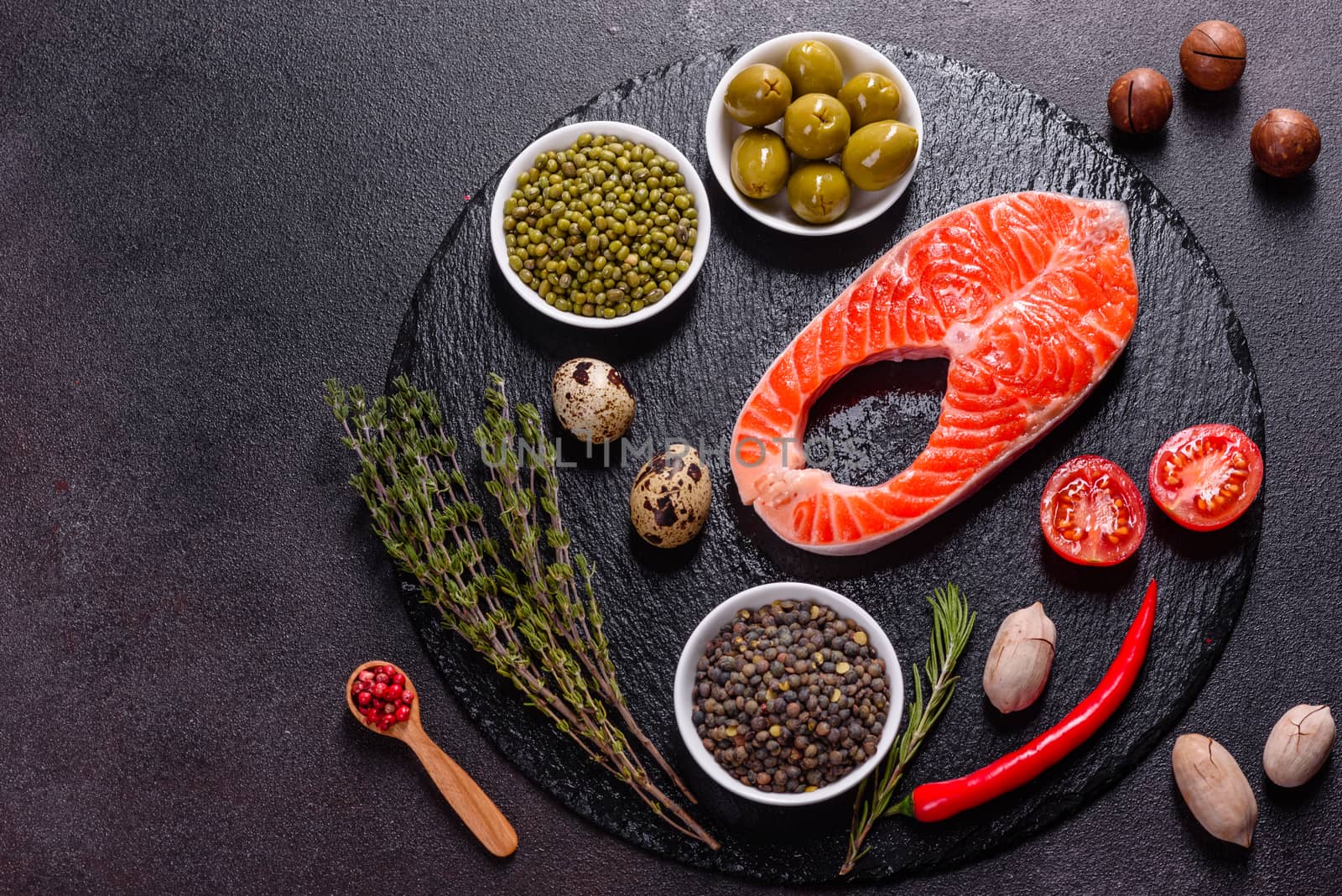Raw trout red fish steak served with herbs and lemon and olive oil on a dark background. Cooking Salmon, sea food. Healthy eating concept