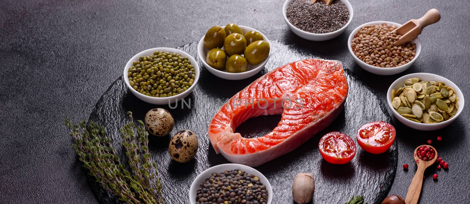 Raw trout red fish steak served with herbs and lemon and olive oil on a dark background. Cooking Salmon, sea food. Healthy eating concept