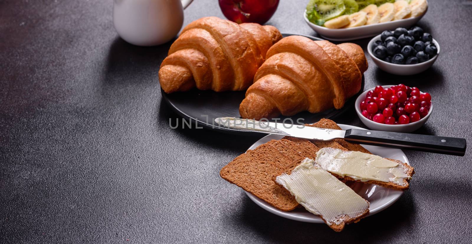 Delicious breakfast with fresh croissants and ripe berries on a beautiful wooden table