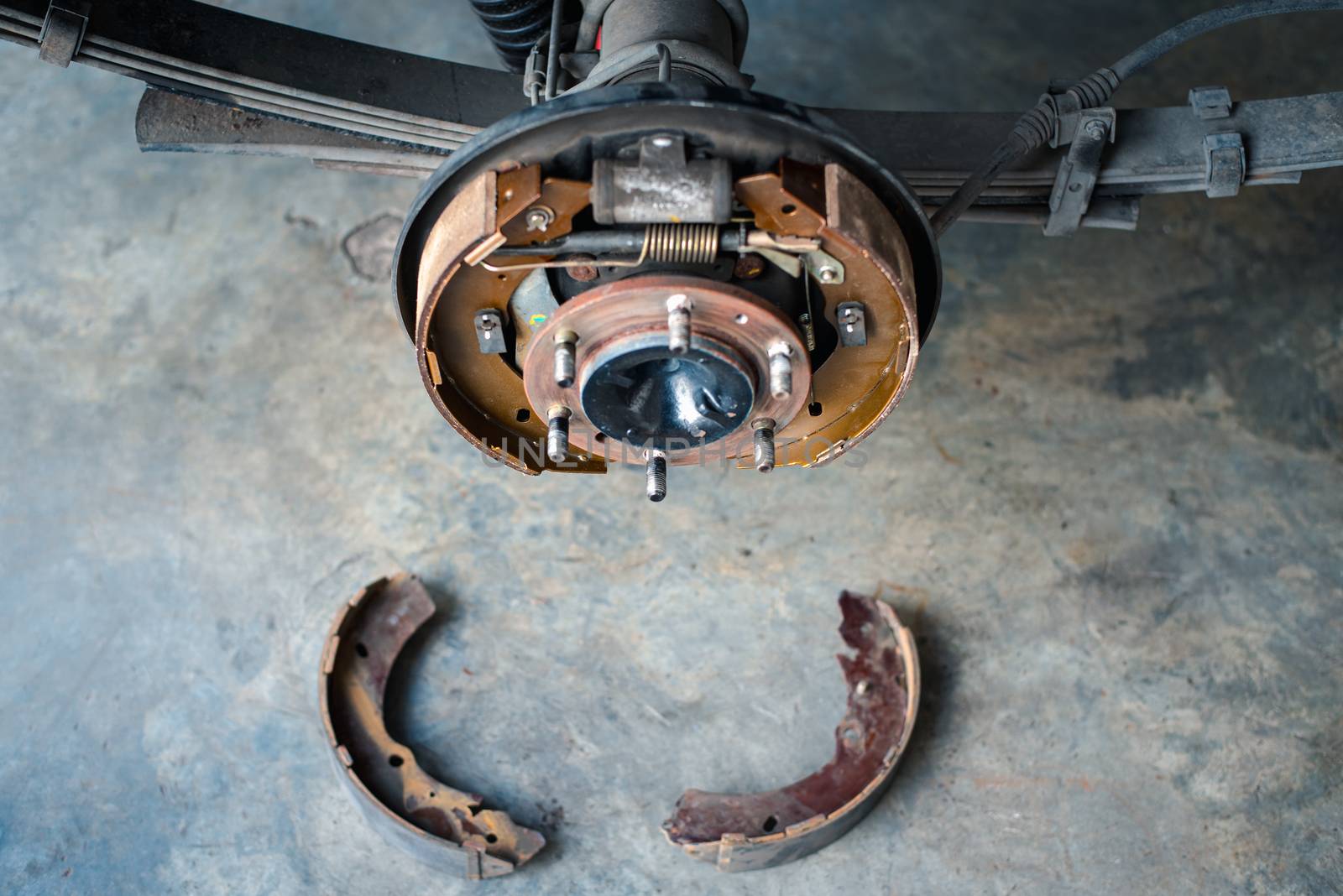 Drum brake and asbestos brake pads at car garage by PongMoji