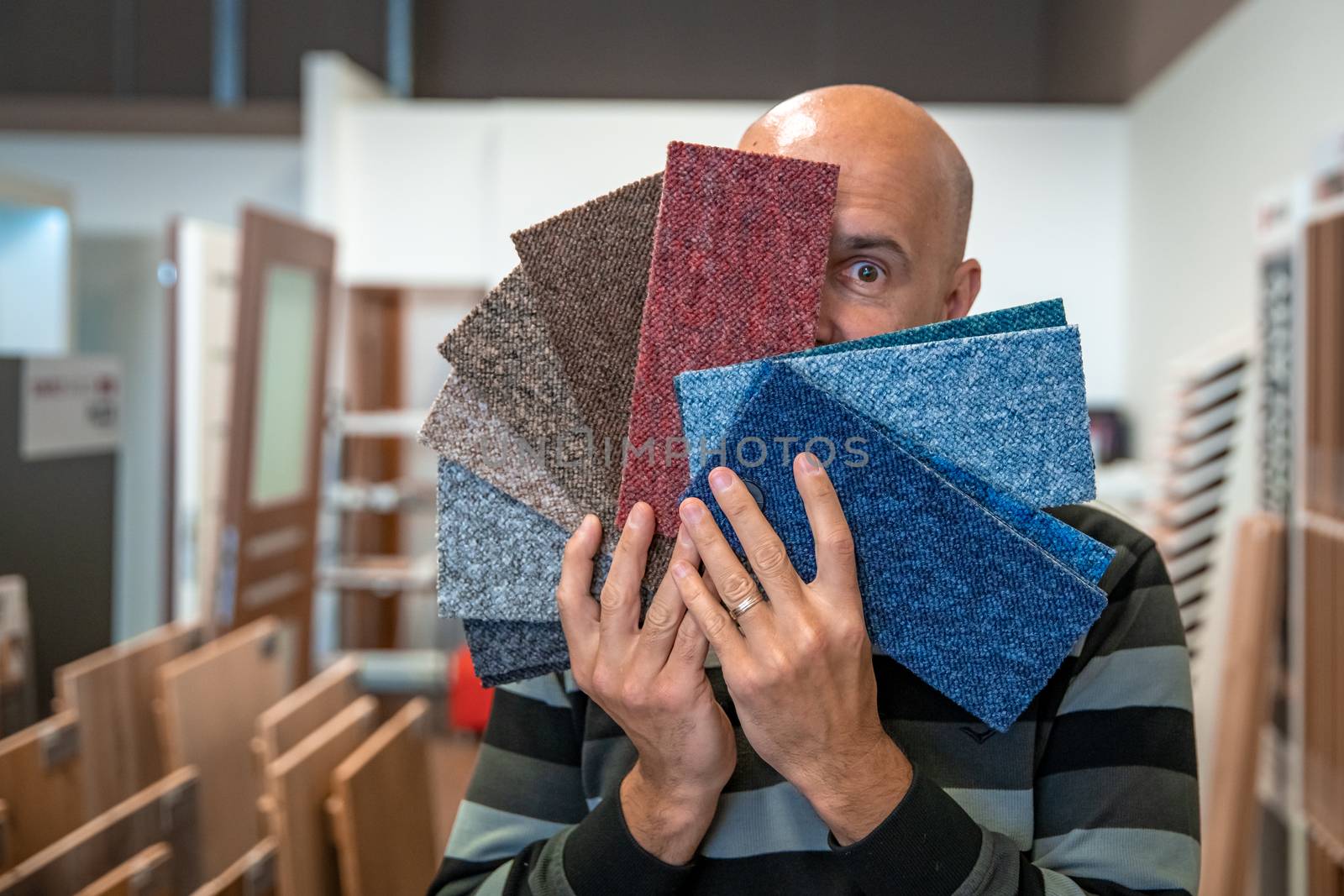 the man chooses the color of the new carpet according to the pattern book in the flooring shop.