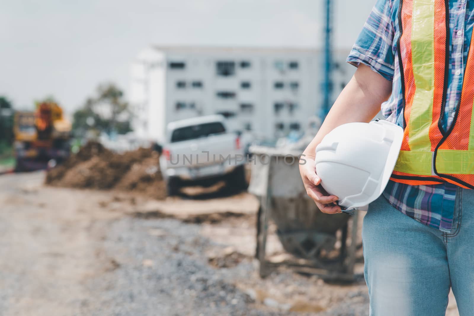 Asian woman civil construction engineer worker or architect with helmet and safety vest happy working at a building or construction site