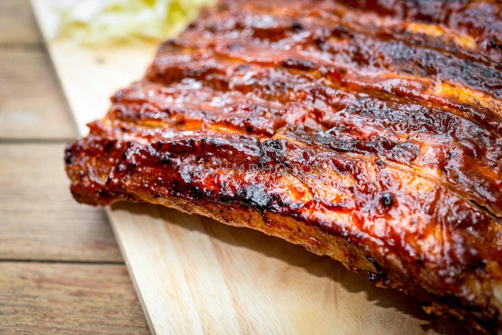 Roasted Pork Spare Ribs Barbecue or Pork Ribs with BBQ Sauce on wooden cutting board in kitchen at Thai street food market or restaurant