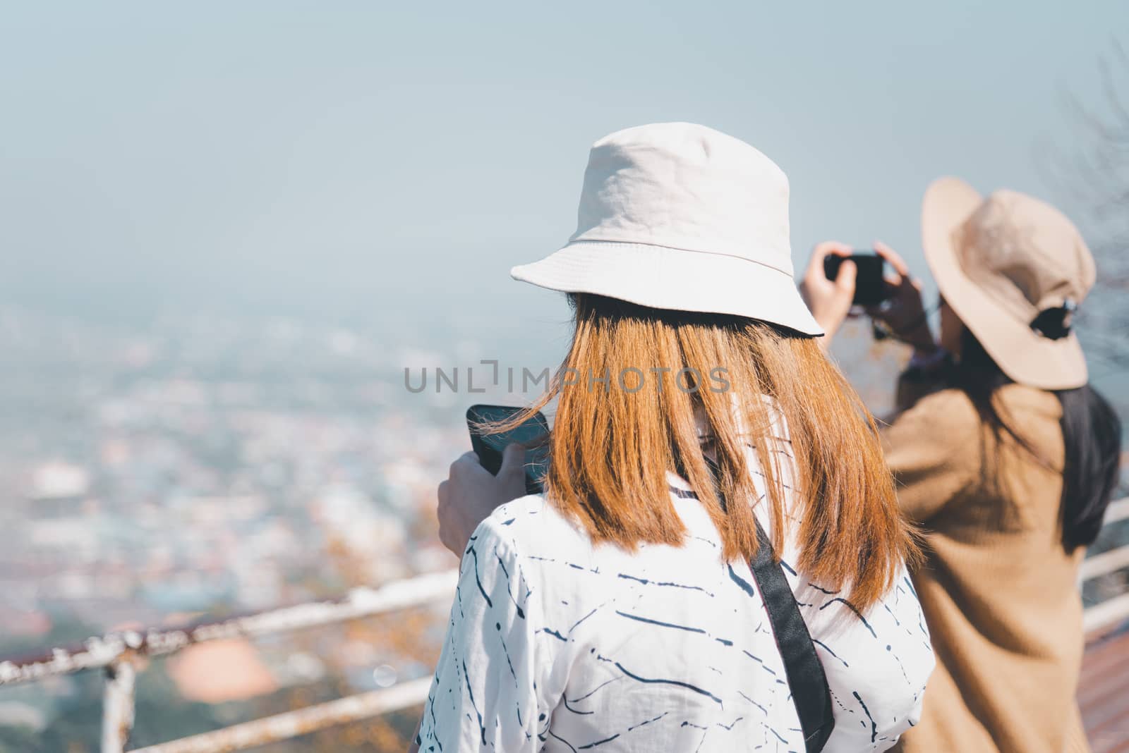 Asian pretty cute woman with hat relax and use smartphone at seaside city landscape viewpoint on mountain with happy and freedom emotion in concept travel, vacation, leisure in life