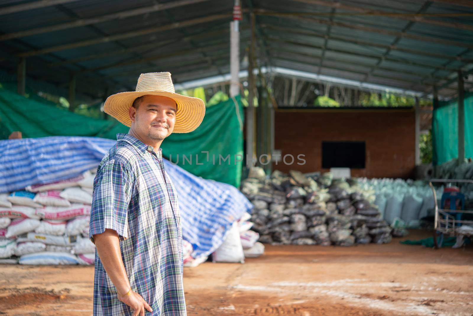 Asian man farmer agriculturist happy at a Fertilizer composting plant with Organic Fertilizer, Compost (Aerobic Microorganisms) from animal waste for use in the organic agriculture industry