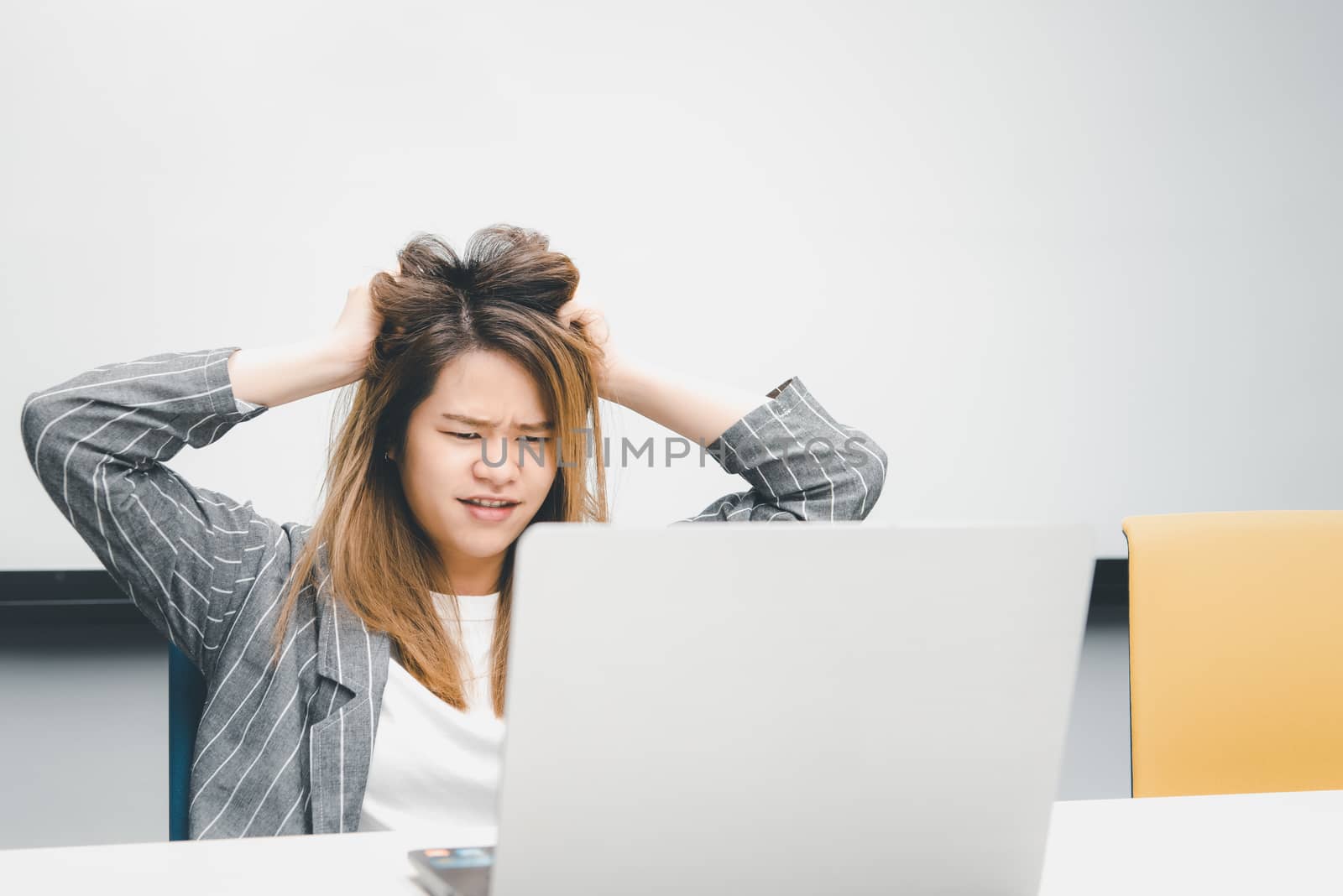 Asian woman is student,businesswoman working by computer notebook, laptop in office meeting room with whiteboard background with annoyed, displeased emotion in concept working woman,unhappy in life