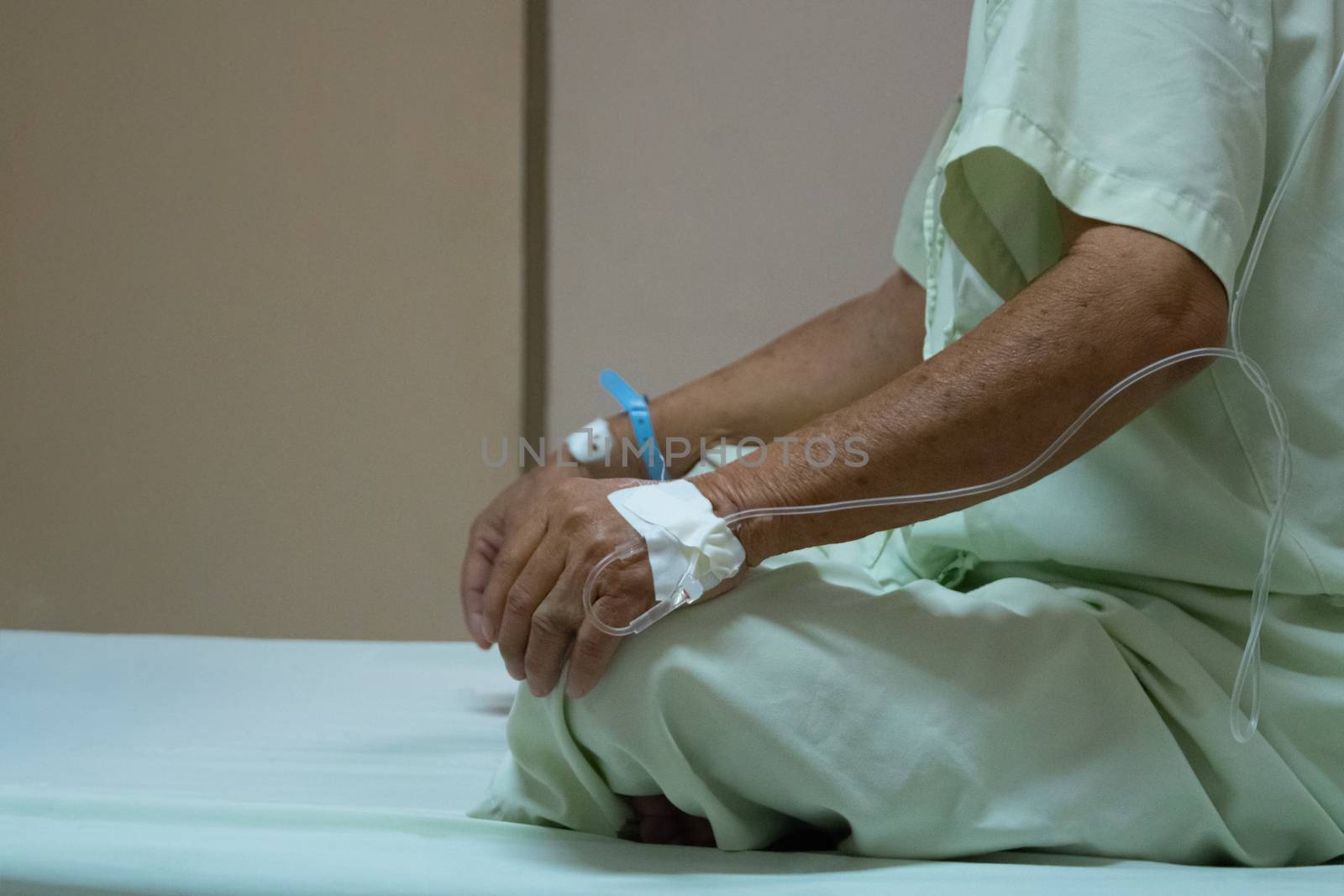 Patient asian elder man 70s with saline intravenous at C-line or A-line on a elderly patient hand on patient bed in intensive care unit (ICU.) room at hospital.